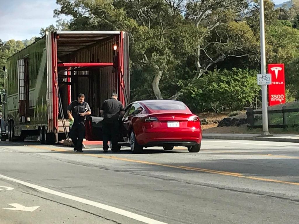 Red Model 3 loaded in trailer to be transported from Tesla HQ