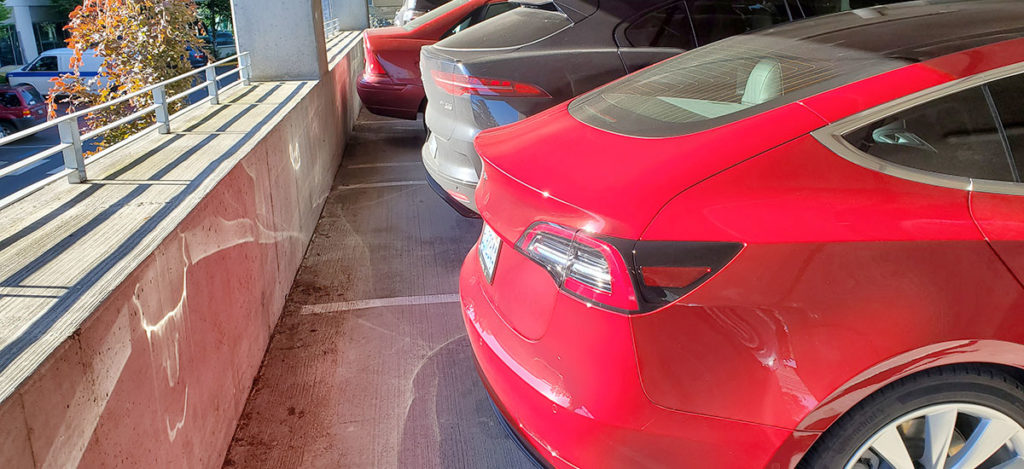 Tesla Model 3 and Jaguar I-Pace standing side-by-side in a parking lot - rear view. Photo by u/NetBrowin via Reddit.