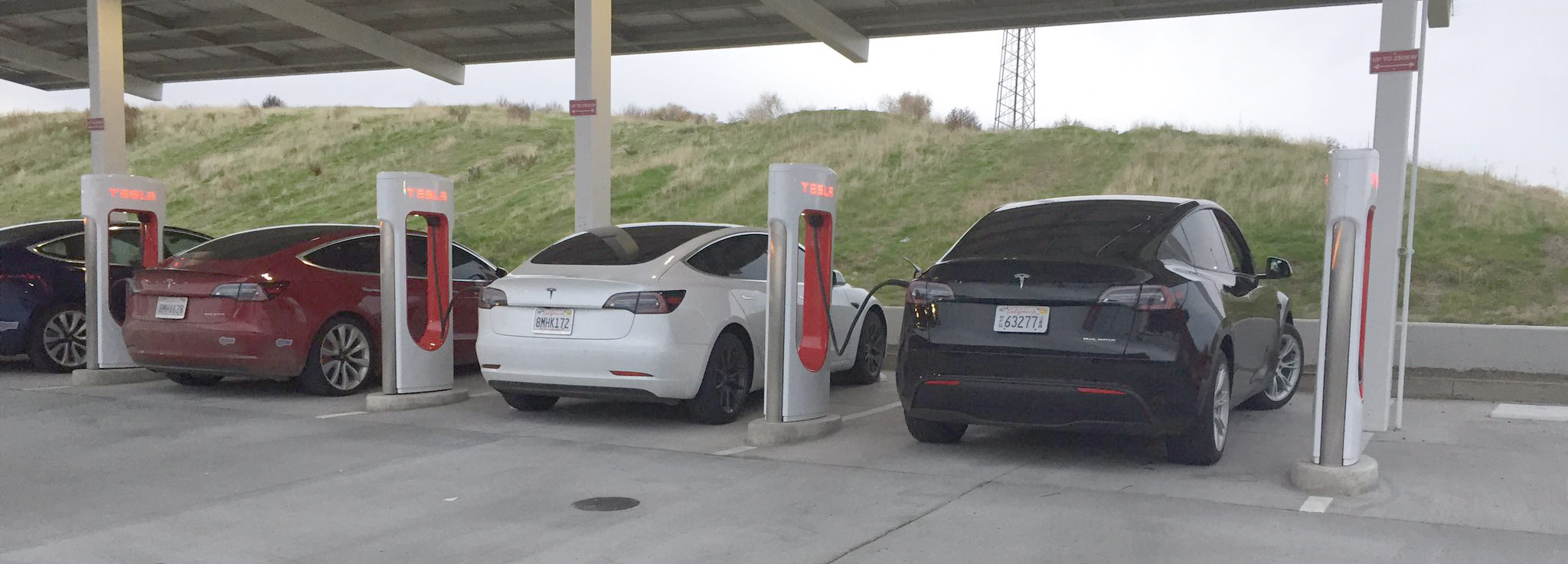 Black Tesla Model Y and white Model 3 charging side-by-side at the Kettleman City Supercharger.