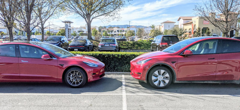 Tesla Model 3 and Tesla Model Y standing opposite each other in a parking lot, giving us an idea of the size comparison of both vehicles.